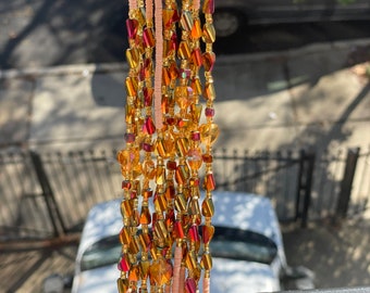 May include: A long strand of peach-colored beads with gold and red glass beads woven in.