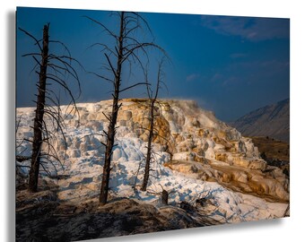 Könnte beinhalten: Ein Landschaftsdruck mit einer natürlichen heißen Quelle mit geschichteten, weißen und hellbraunen Formationen. Kahle Bäume stehen im Vordergrund vor einem blauen Himmel und fernen Bergen. Das Bild ist ein Wandkunstdruck.