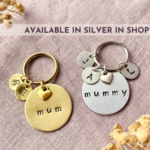 May include: Two circular metal keychains, one gold-toned and one silver-toned. The gold keychain features the word mum and two smaller discs with letters R and E. The silver keychain features the word mummy and three discs with letters J, A, and L.