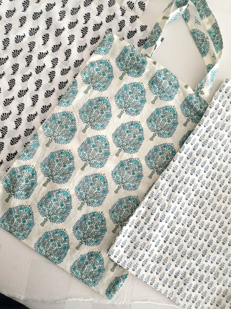 Puede incluir: Tres bolsas de tela con diferentes patrones. La primera bolsa tiene un fondo blanco con dise&ntilde;os de hojas negras. La segunda bolsa tiene un fondo blanco con dise&ntilde;os de &aacute;rboles verdes y azules. La tercera bolsa tiene un fondo blanco con peque&ntilde;os dise&ntilde;os florales azules.