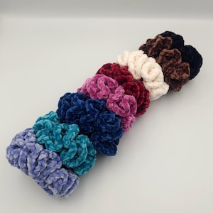 May include: A set of ten colorful scrunchies made of soft, fuzzy fabric. The scrunchies are arranged in a row, with the darkest color at the top and the lightest color at the bottom. The colors are black, brown, white, burgundy, pink, dark blue, teal, and light blue.