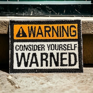 Könnte beinhalten: Ein schwarz-weißes Warnschild mit einem gelben Dreieck und dem Text "WARNING CONSIDER YOURSELF WARNED".