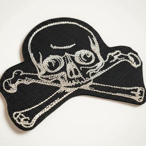 Patch bordado com caveira e ossos cruzados em estilo gótico.