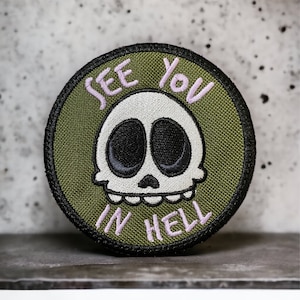 May include: A green embroidered patch with a white skull and the text "See You In Hell" in pink.