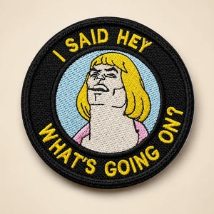 May include: Embroidered patch with a black border and the text "I SAID HEY WHAT'S GOING ON?" in yellow. The patch features a cartoon image of a blonde person with a stern expression, set against a light blue background.