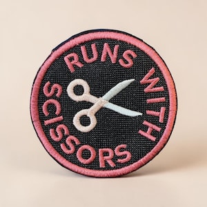 Broderad lapp med roligt hantverksmärke "Runs With Scissors"
