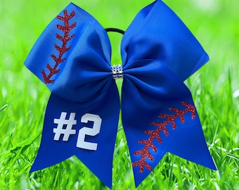 May include: A blue cheer bow with red glitter baseball stitching and the number "#2" in white glitter.