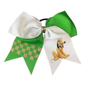 May include: A large hair bow featuring a white and green design with a gold glitter checkered pattern and a cartoon image of Pluto. The bow is attached to a black elastic band.