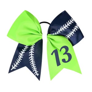 May include: A vibrant green and navy blue softball bow with white stitching details. The bow features the number 13 in navy blue on one of the green ribbons. This accessory is perfect for sports enthusiasts.