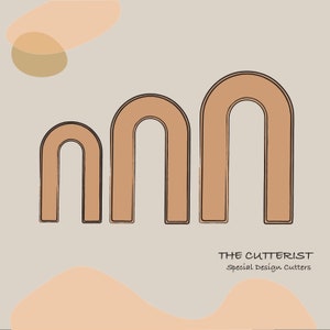 May include: Three brown arch-shaped cookie cutters with black outlines are displayed on a beige background. The text "THE CUTTERIST Special Design Cutters" is at the bottom. The cutters are in varying sizes.
