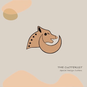 Puede incluir: Ilustración marrón claro de un animal parecido a un zorro con forma de media luna. El zorro tiene contornos negros y formas de diamante en su cuerpo. El texto "THE CUTTERIST Special Design Cutters" está debajo.