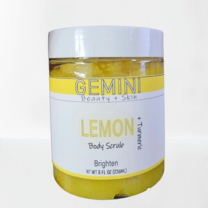 Puede incluir: Un tarro amarillo de exfoliante corporal de limón y cúrcuma con tapa blanca y etiqueta que dice "GEMINI Beauty + Skin LEMON + Turmeric Body Scrub Brighten NT WT 8 FL OZ (236ML)"
