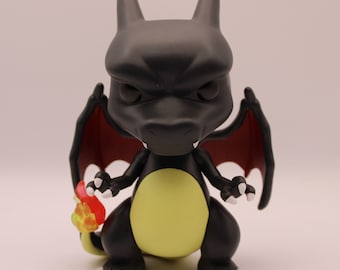 May include: Black and yellow Pokemon figure with red wings and a flame tail. The figure is a stylized version of Charizard, a popular Pokemon character.