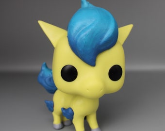 May include: A yellow and blue vinyl figure of a cartoon horse with a blue mane and tail. The figure has large black eyes and a small, pointed nose.