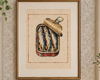 May include: A framed wall print featuring an illustration of an open tin of sardines with a metallic lid. The artwork is displayed in a gold frame hanging on a wall. The print includes the text "SARDINES" in small black lettering.