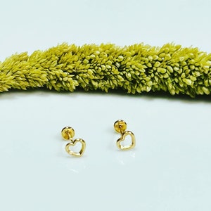 May include: A pair of gold heart-shaped stud earrings with a white background.