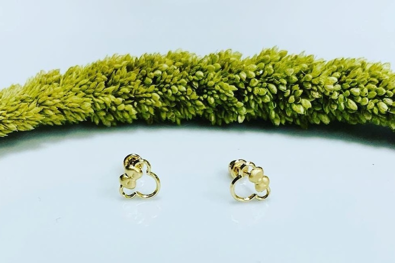 May include: A pair of gold-tone earrings with a cloud-shaped design. Each earring features three small round beads.