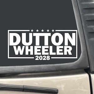 May include: White vinyl sticker with the text "Dutton Wheeler 2028" in a black rectangle with five white stars above the text.
