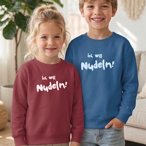Könnte beinhalten: Ein bordeauxrotes Langarm-Sweatshirt und ein blaues Langarm-Sweatshirt, beide mit dem weißen Schriftzug "ich will Nudeln!" auf der Brust. Die Kleidungsstücke verfügen über einen Rundhalsausschnitt sowie gerippte Bündchen an Ärmeln und Saum.