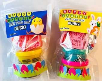 May include: Two clear plastic bags filled with Easter-themed play dough kits. The first bag contains yellow play dough, a chick-shaped cookie cutter, and a chick-shaped sticker. The second bag contains blue play dough, a bunny-shaped cookie cutter, and a bunny-shaped sticker. Both bags have a Happy Easter banner and the text "Make your own chick!" and "Make your own bunny!"
