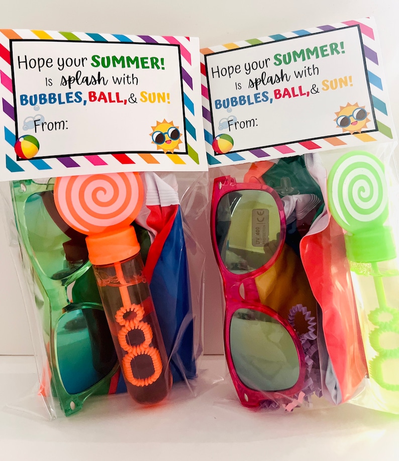 May include: Two clear plastic bags filled with summer themed party favors. Each bag contains a pair of sunglasses, a beach ball, a bubble wand, and a lollipop. The bags are decorated with a tag that says "Hope your summer is splash with bubbles, ball, & sun!"