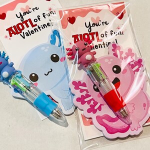 K&ouml;nnte beinhalten: Zwei Valentinstagskarten mit Stiften zum Thema Axolotl. Eine Karte zeigt einen blauen Axolotl und Stift, die andere einen rosa Axolotl und Stift. Die Karten lauten "You're AIOTL of fun, Valentine!"