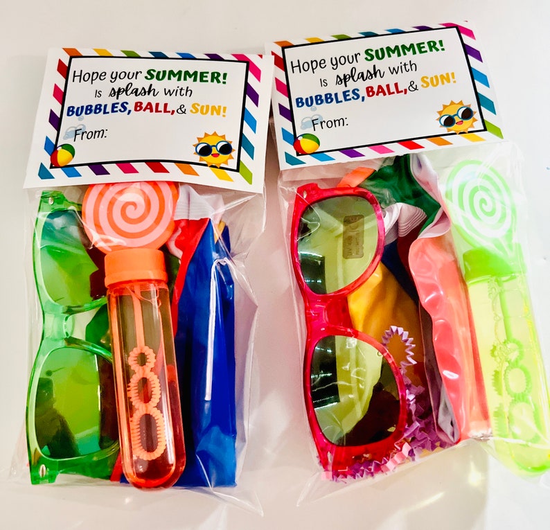 May include: Two clear plastic bags filled with summer themed party favors. Each bag has a printed tag that says "Hope your SUMMER! is splash with BUBBLES, BALL, & SUN!"  The bags contain sunglasses, a bubble wand, a beach ball, and a lollipop.