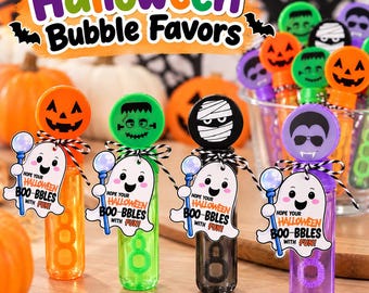 May include: Four cylindrical bubble wands in orange, green, black, and purple, each topped with a Halloween character cap. Attached ghost-shaped tags feature the text "Hope your Halloween Boo-bbles with fun!" tied with black and white twine.