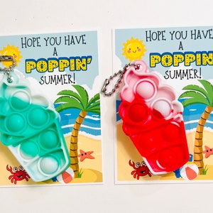 K&ouml;nnte beinhalten: Zwei bunte Pop-it-Schl&uuml;sselanh&auml;nger mit Sommerthema. Die Schl&uuml;sselanh&auml;nger sind in Form von Eiswaffeln gestaltet und haben ein wei&szlig;-blaues Pop-it und ein wei&szlig;-rotes Pop-it. Die Schl&uuml;sselanh&auml;nger sind an Karten mit dem Text "Ich hoffe, du hast einen tollen Sommer!" befestigt.