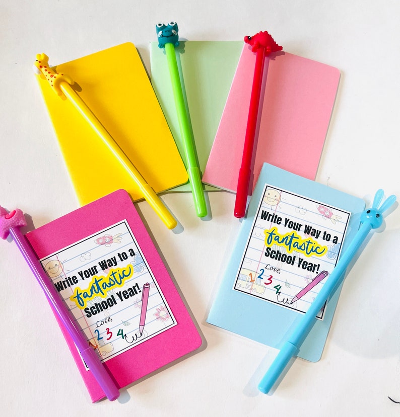 May include: Five small notebooks with colorful covers and pens with animal toppers. Each notebook has a sticker on the front that says "Write Your Way to a Fantastic School Year!" and includes a number sequence.
