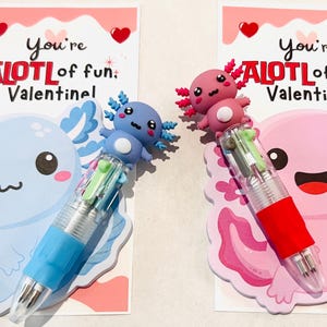K&ouml;nnte beinhalten: Zwei Valentinstagskarten mit Axolotl-Designs. Eine Karte zeigt einen blauen Axolotl mit einem blauen Stift, die andere einen rosa Axolotl mit einem roten Stift. Jede Karte tr&auml;gt den Text "You're ALOTL of fun, Valentine!"