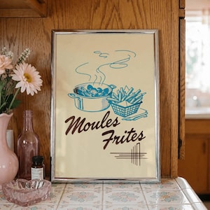 May include: A rectangular framed print with a cream background featuring a blue line art illustration of a pot of mussels and a basket of fries. The text "Moules Frites" is printed in a dark brown script font below the food illustrations.