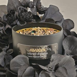 Op de afbeelding: Zwarte kaars met gouden glitter en een kristal ingebed in de was. De kaars is gelabeld met "Abaddon Judgment and Justice" met de website www.magicalmystic.com.
