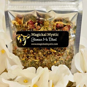 May include: A small clear plastic bag filled with a blend of dried herbs, flowers, and crystals. The bag has a black label that reads "Magickal Mystic Glamour Me Blend" and "www.magickalmystic.com".