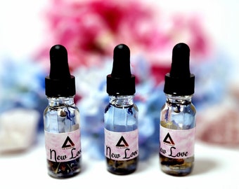 May include: Three small glass bottles with black dropper tops filled with a clear liquid and dried flowers. Each bottle has a white label with a pink triangle and the text "New Love".