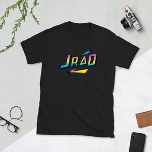 May include: Black t-shirt with a retro-style graphic design featuring the word "JRAD" in colorful, layered letters.