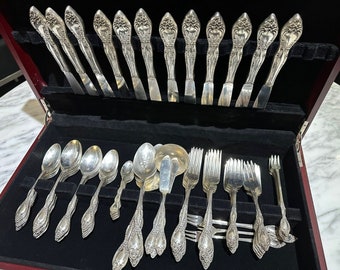 May include: A set of silver flatware in a wooden case. The flatware includes knives, forks, and spoons. The case is lined with black velvet.