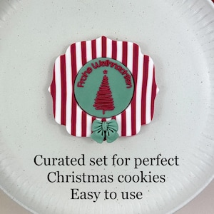 Könnte beinhalten: Ein Weihnachts-Ausstecher-Set mit rot-weißem Streifendesign, einem grünen Weihnachtsbaum und einer grünen Schleife. Der Text auf dem Ausstecher lautet "Frohe Weihnachten". Das Set befindet sich auf einem weißen Teller mit einem rot-grünen Band.