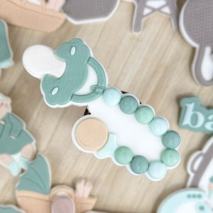 May include: A set of 15 green and white baby shower decorations. The decorations include a baby bottle, a pacifier, a baby rattle, a baby carriage, a baby in a crib, a baby's onesie, a baby's hat, a baby's booties, a baby's bib, a baby's blanket, a baby's toy, a baby's food, a baby's bath, a baby's diaper, and a baby's clothes.