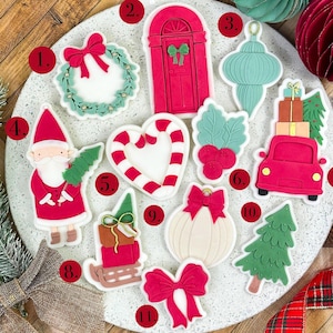 Può includere: Una collezione di formine per biscotti a tema natalizio, tra cui una ghirlanda, una porta, un ornamento, Babbo Natale, un bastoncino di zucchero, agrifoglio, un'auto con regali, una slitta, una zucca, un albero e un fiocco.