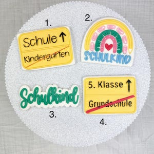 Könnte beinhalten: Vier dekorierte Kekse mit Designs zum Thema Schule. Ein Keks ist ein gelbes Straßenschild mit den Texten "Schule" und "Kindergarten". Ein weiterer ist ein Regenbogen mit dem Wort "Schulkind". Der dritte Keks sagt "Schulkind". Der vierte Keks ist ein gelbes Straßenschild mit "5. Klasse" und "Grundschule".