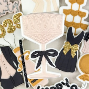 Könnte beinhalten: Eine Sammlung von Neujahrs-Zuckerplätzchen, die mit goldenem Glitzer, schwarzem und rosa Zuckerguss verziert sind. Die Plätzchen zeigen ein Champagnerglas, einen Smoking, ein Kleid, eine Champagnerflasche und die Worte "Let's Party", "2023" und "Happy New Year".