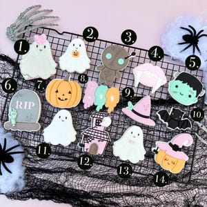 May include: A collection of Halloween-themed cookies, including ghosts, pumpkins, a tombstone, a voodoo doll, and a witch's hat. The cookies are decorated with various colors and designs, perfect for a spooky celebration.