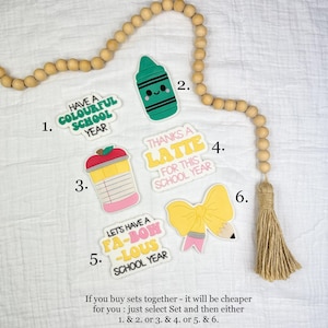 Puede incluir: Una colección de pegatinas coloridas con temática escolar. Las pegatinas incluyen un crayón, una taza de café, un lazo con un lápiz y frases como "Have a Colourful School Year" y "Thanks a Latte for this School Year."