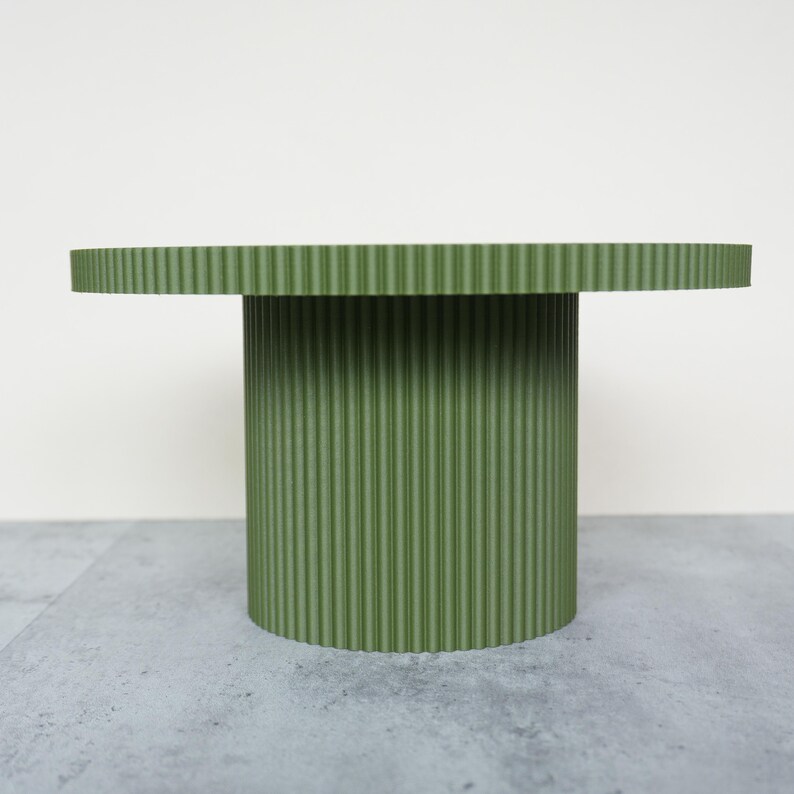 May include: A green, round side table with a ribbed texture. The table has a circular top and a cylindrical base. The table is approximately 20 inches in diameter and 18 inches tall.