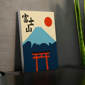 Könnte beinhalten: Ein beigefarbener Leinwanddruck mit einer stilisierten Illustration des Mount Fuji, einer roten Sonne und einem roten Torii-Tor. Die japanischen Schriftzeichen "富士山" sind oben auf dem Druck in Schwarz geschrieben.