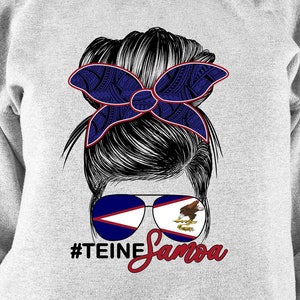 Könnte beinhalten: Grauer Pullover mit einem Aufdruck einer Frau mit einem Dutt und einer blauen und roten Schleife. Die Frau trägt eine Sonnenbrille mit der Flagge von Amerikanisch-Samoa. Der Text "#TEINE Samoa" befindet sich unter dem Aufdruck.