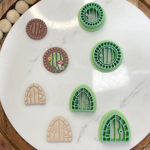 May include: Set of seven cookie cutters in green and brown, featuring different styles of doors. The cutters are arranged on a white marble surface.