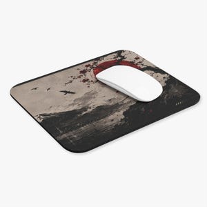 May include: A rectangular mouse pad featuring a graphic illustration of a landscape with a large red sun, dark tree branches, and flying birds. A smooth white computer mouse rests on the surface of the pad, which has rounded corners.