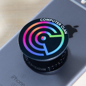 Może przedstawiać: Czarny popsocket do telefonu z wzorem w postaci tęczowego koła i tekstem "COMPUTER CLAN".